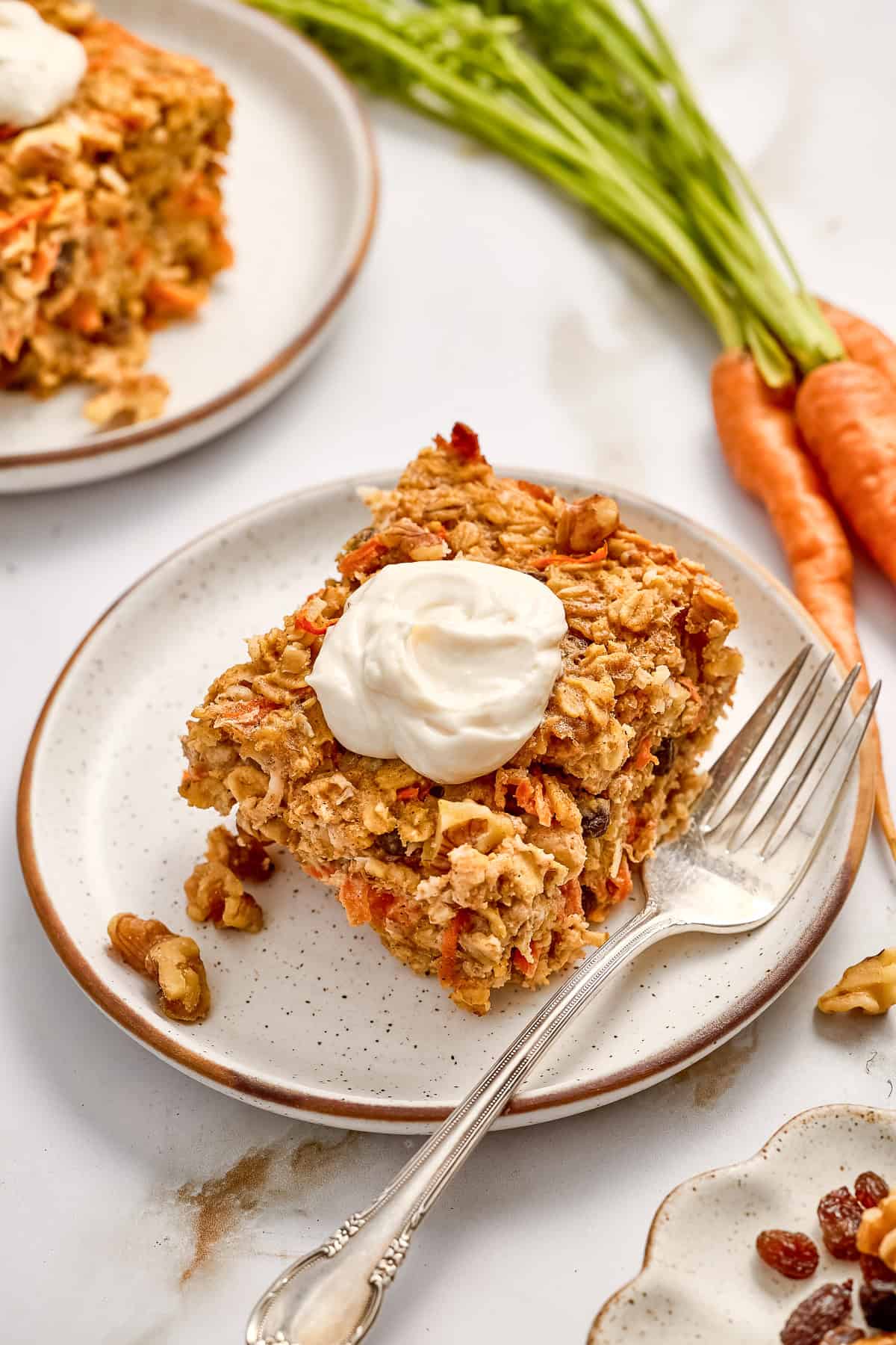 Slice of carrot cake baked oats with cream cheese frosting on a plate.