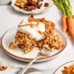 Carrot cake oats with frosting on a plate with a fork with a bite on it.