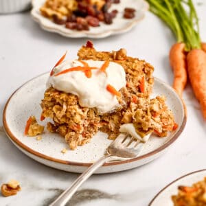 Carrot cake oats with frosting on a plate with a fork with a bite on it.