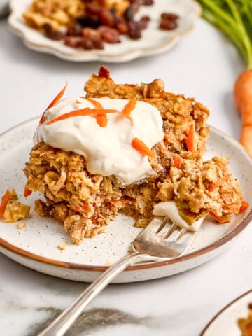 Carrot cake oats with frosting on a plate with a fork with a bite on it.