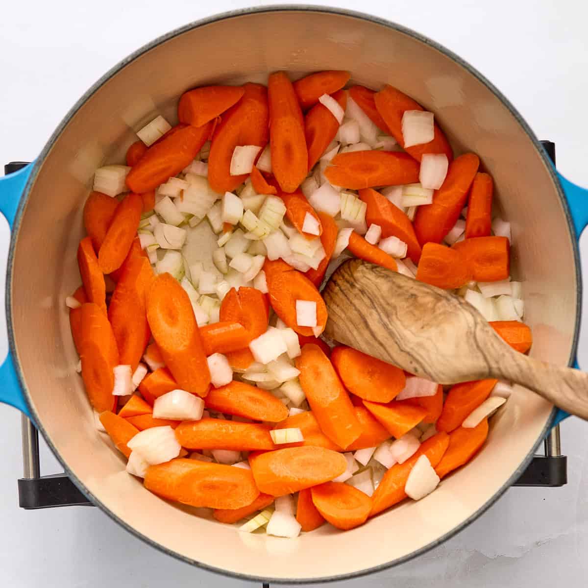 Carrots and onions cooking in extra virgin olive oil in a large pot.