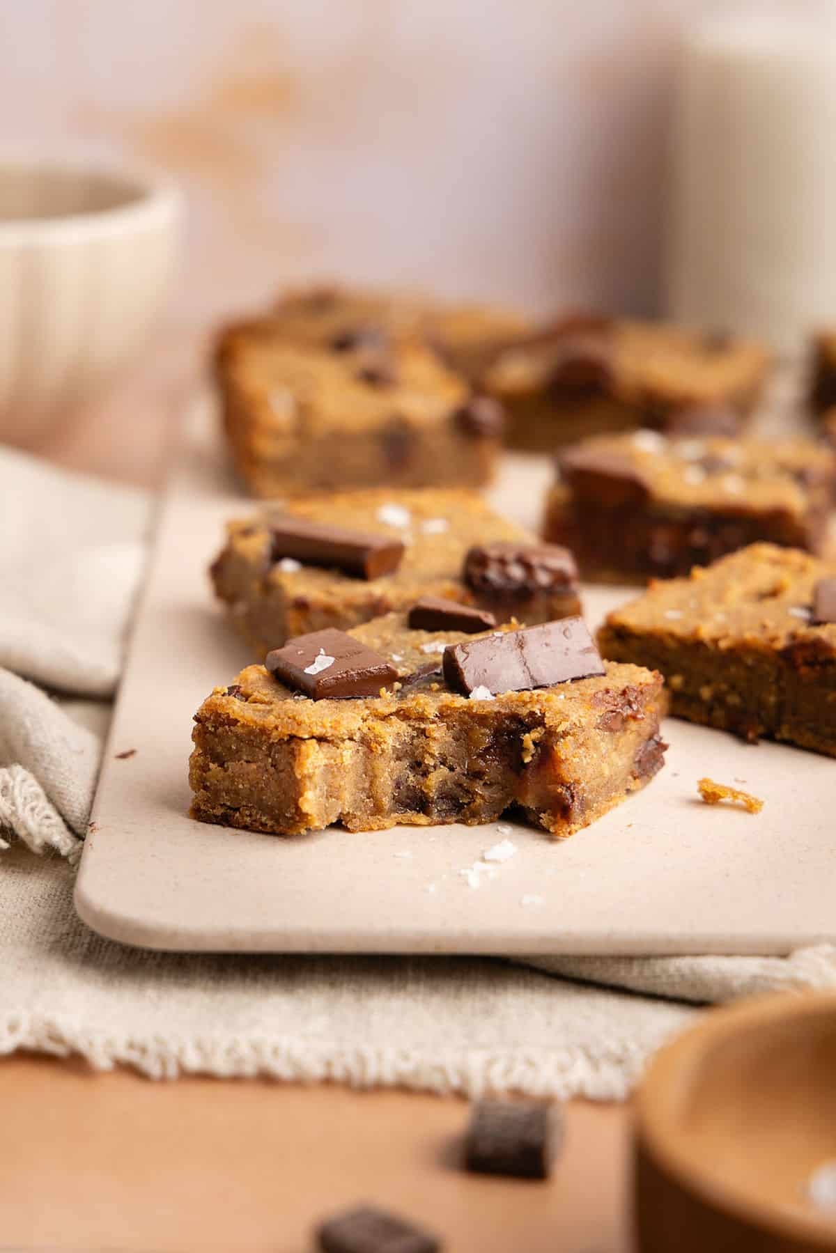 Chickpea vegan blondie with a bite taken out of it on a cutting board.