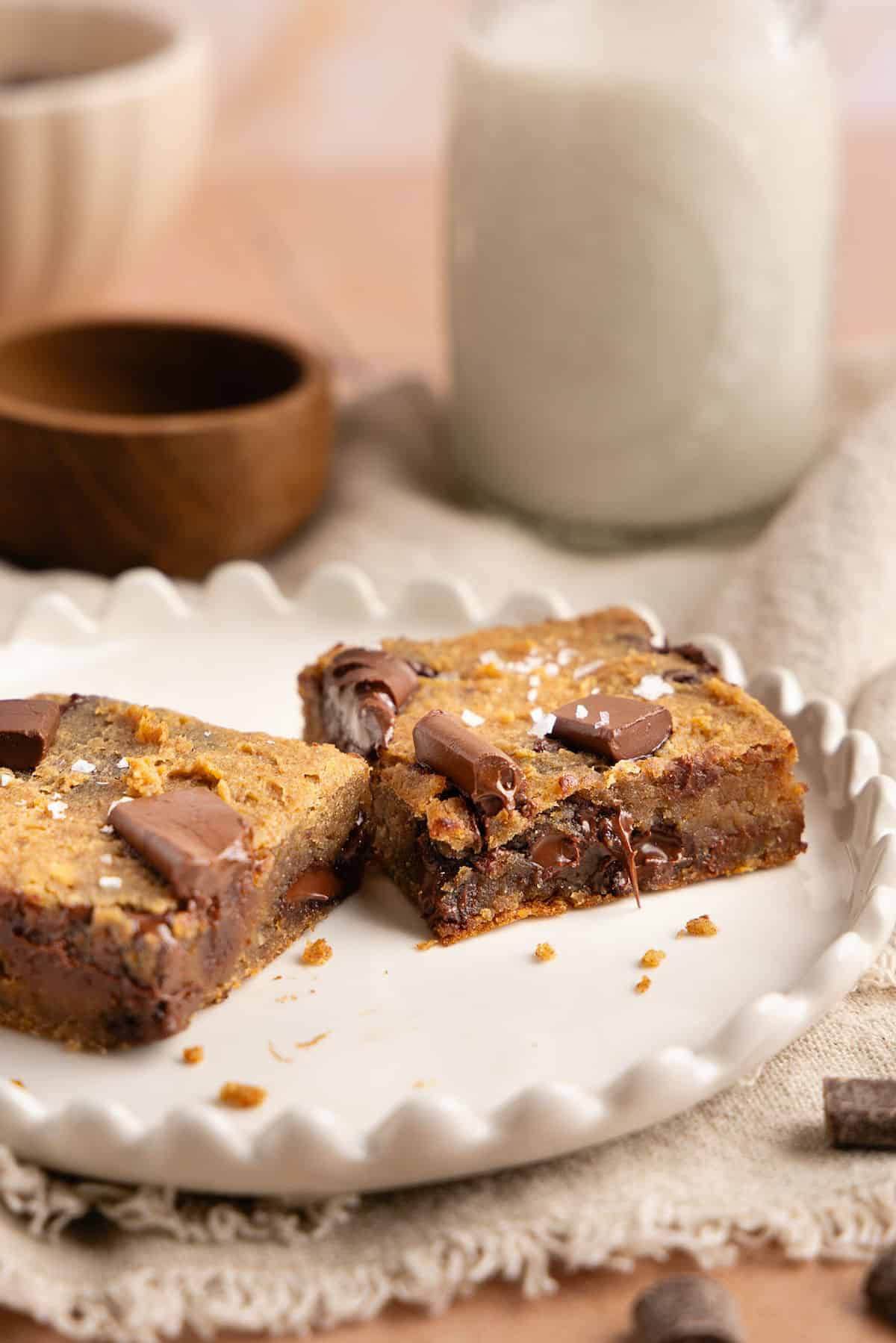 Plate with two chickpea blondies in front of a glass jar of milk.