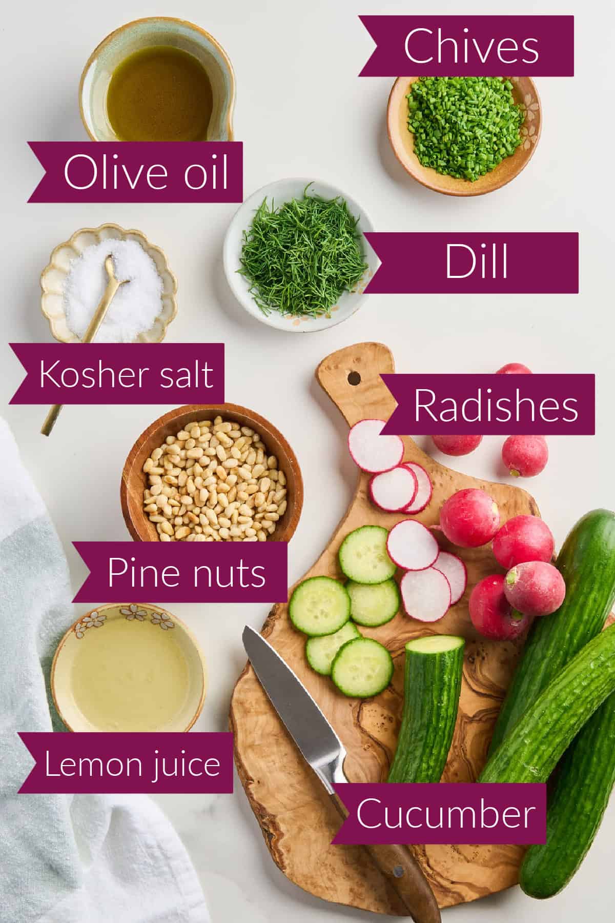 Olive oil, chives, salt, dill, pine nuts, radishes, lemon juice, and cucumbers with labels.