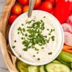 Creamy cottage cheese dip with chives in a bowl with a spoon on a veggie tray.