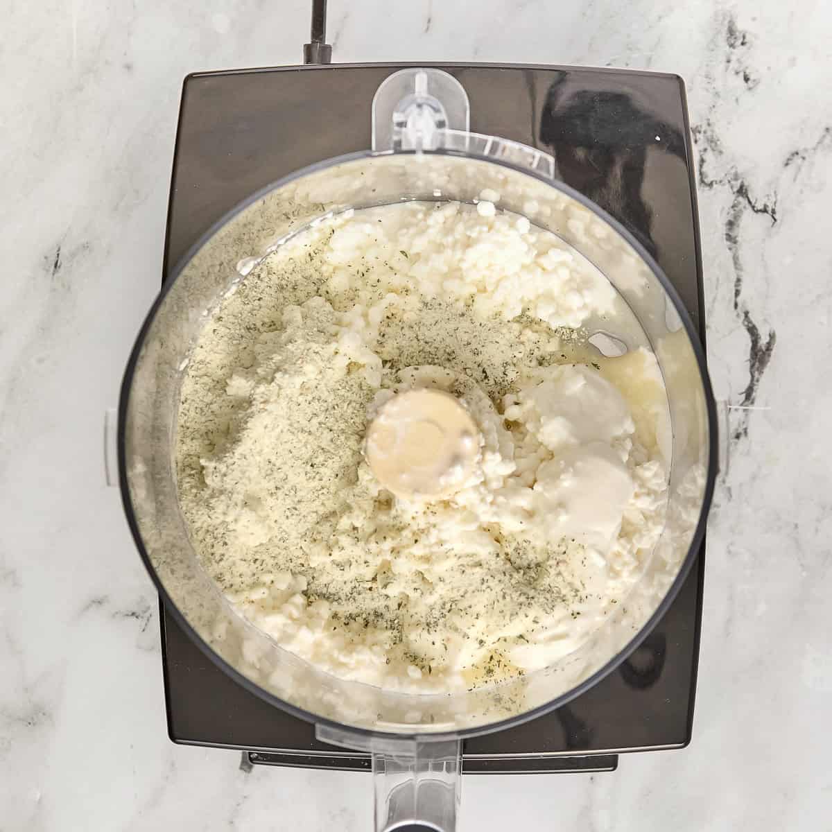 Cottage cheese, yogurt, ranch seasoning, and lemon juice in a food processor before being blended.