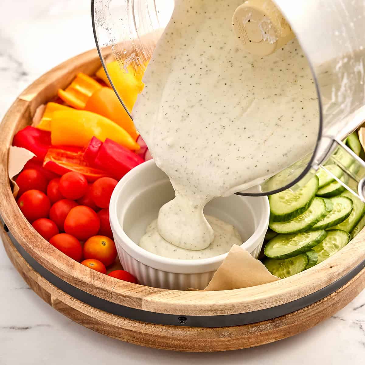 Cottage cheese ranch dip being poured into a bowl on a veggie tray.