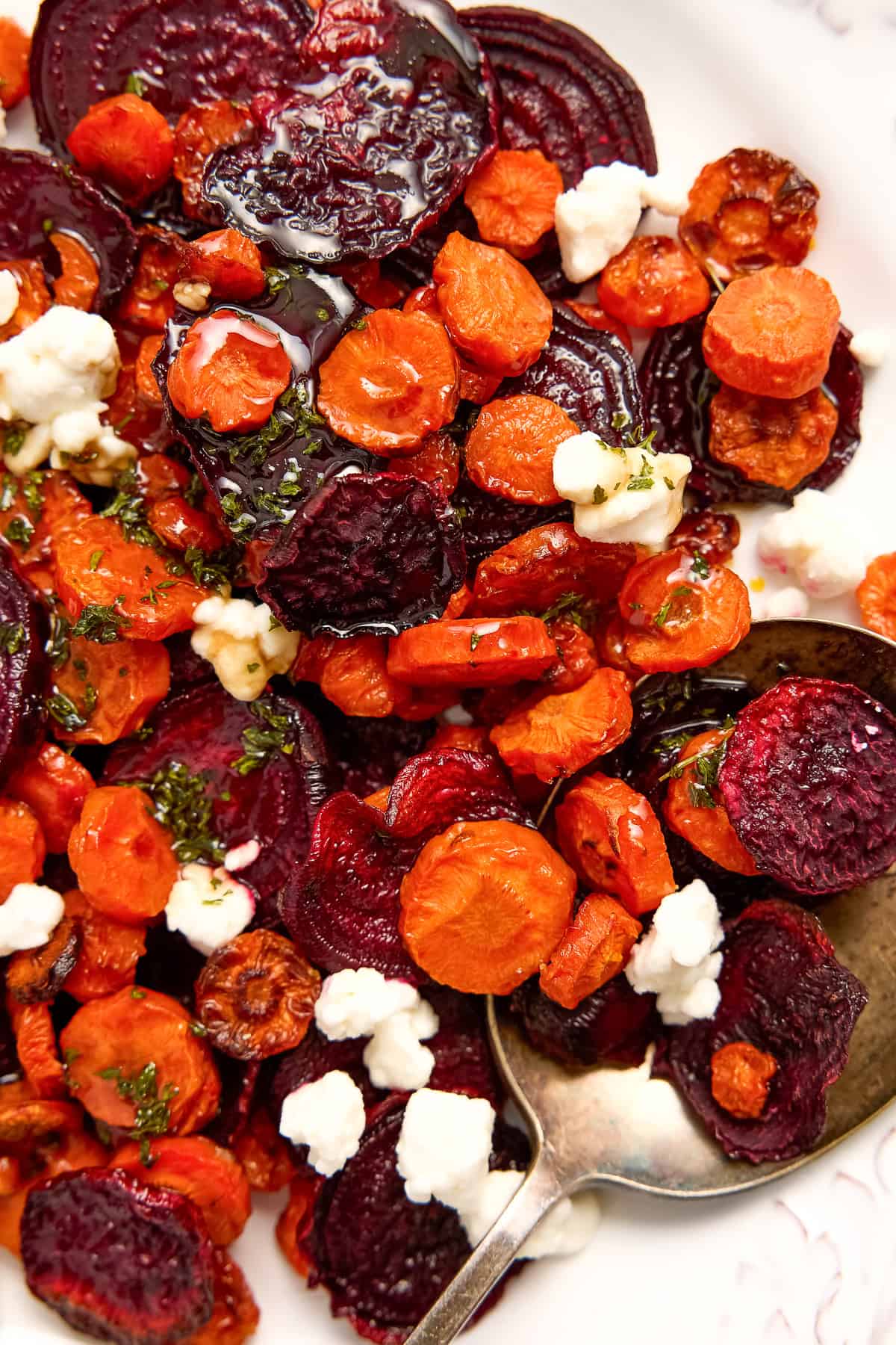 Beets, carrots, goat cheese, and honey balsamic glaze on a plate with a spoon.