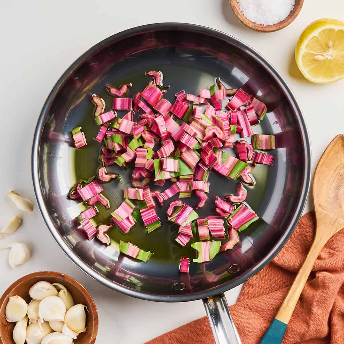 Red chard stem slices cooking in olive oil in a skillet.