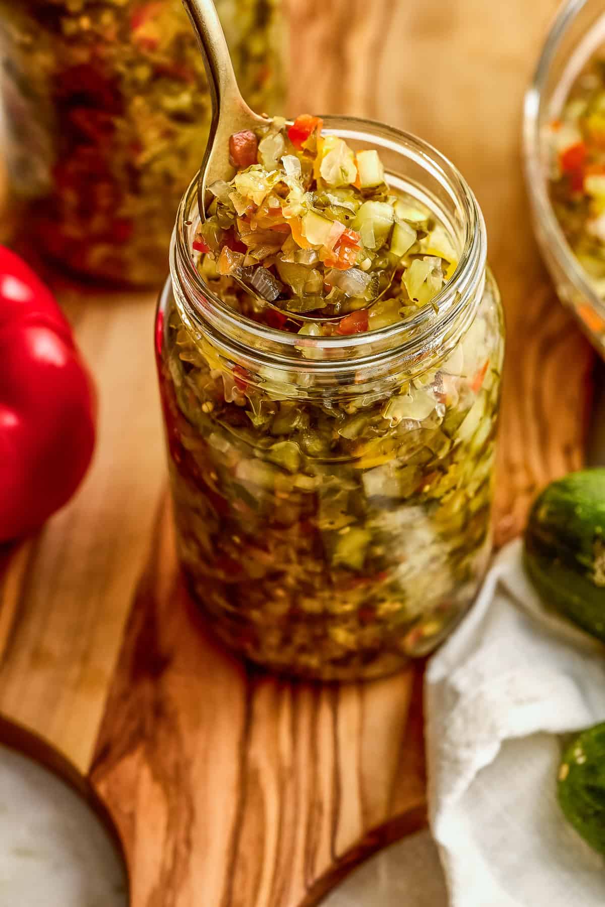 Homemade sweet relish recipe on a spoon being lifted out of a glass jar.