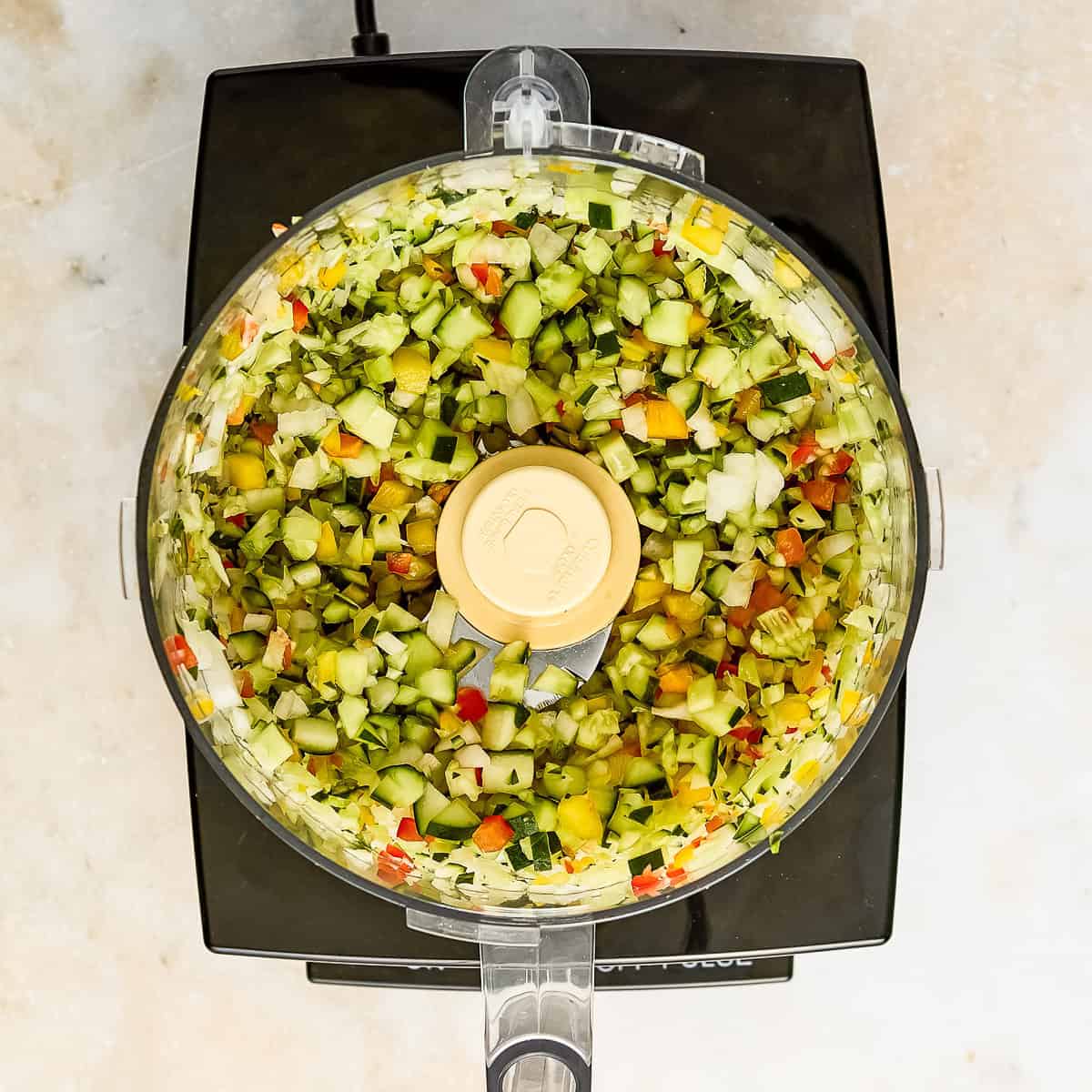 Vegetables for sweet relish in a food processor after being pulsed into small pieces.