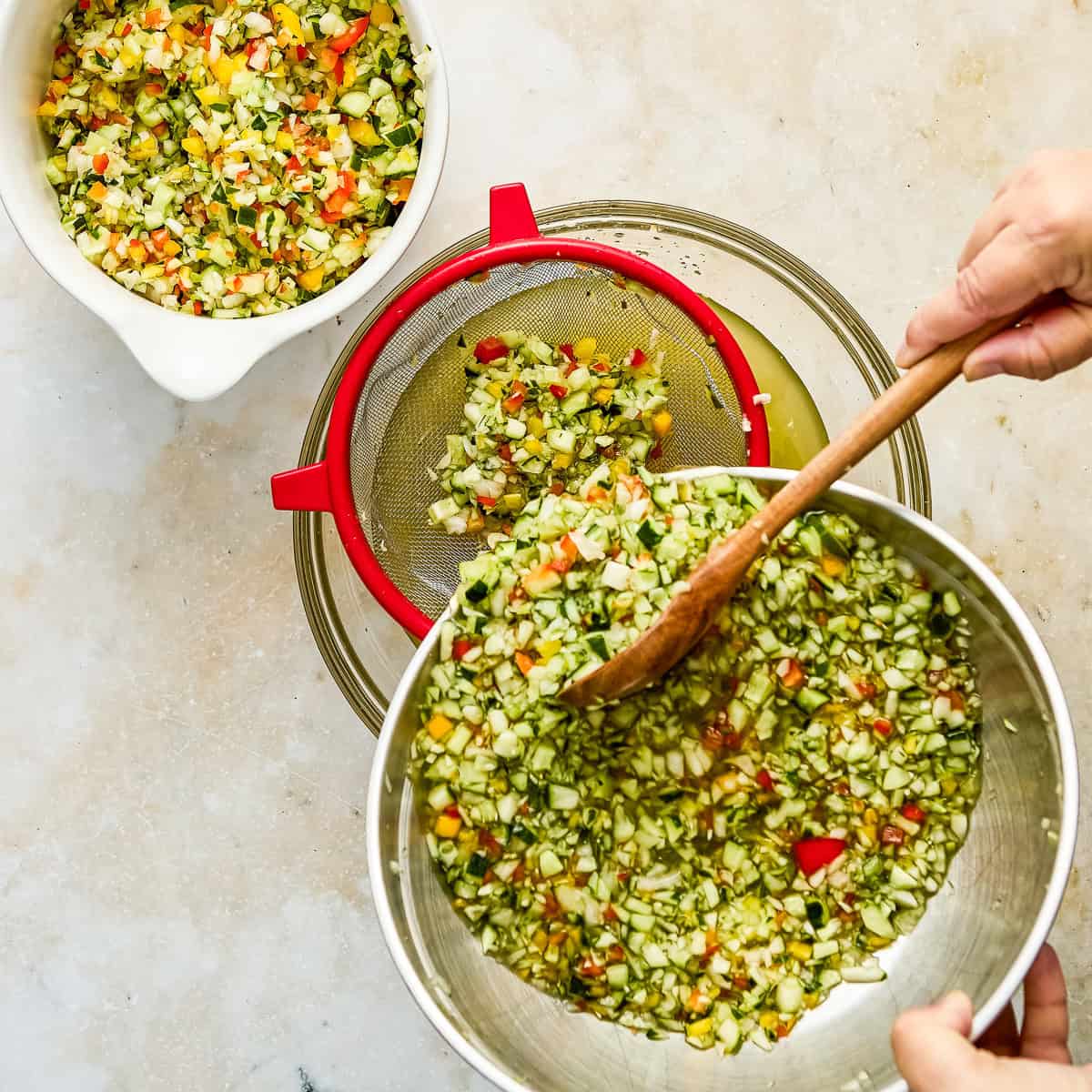Woman spooning relish ingredients into a mesh strainer over a bowl.