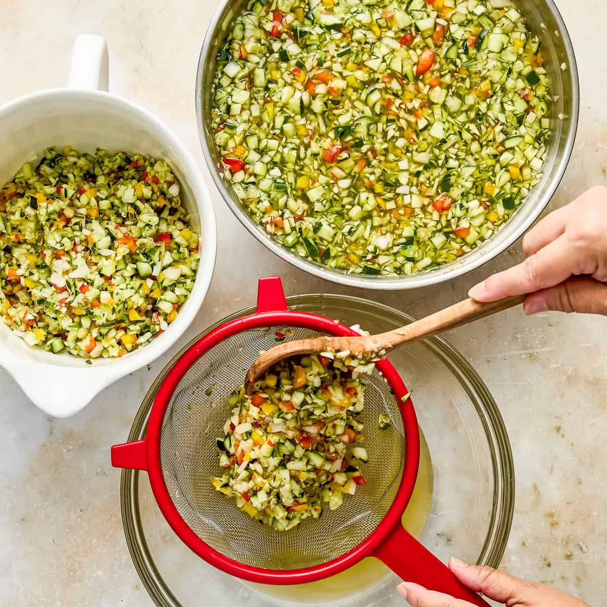 Woman pressing soaked vegetables into a mesh strainer to release water.
