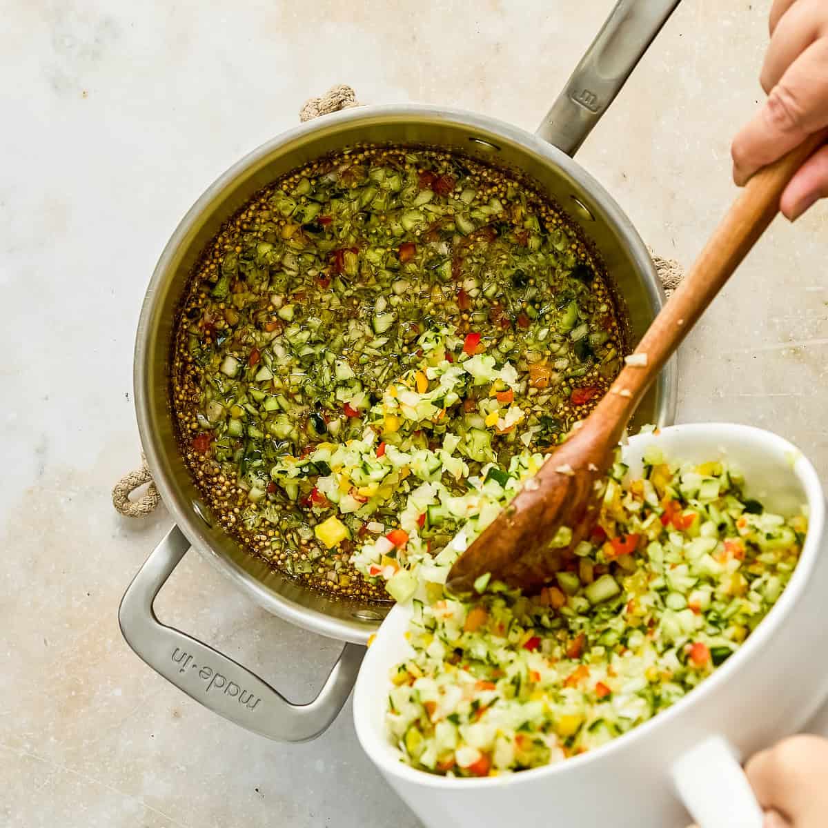 Woman spooning vegetables into a pot with vinegar, sugar, and seasonings.