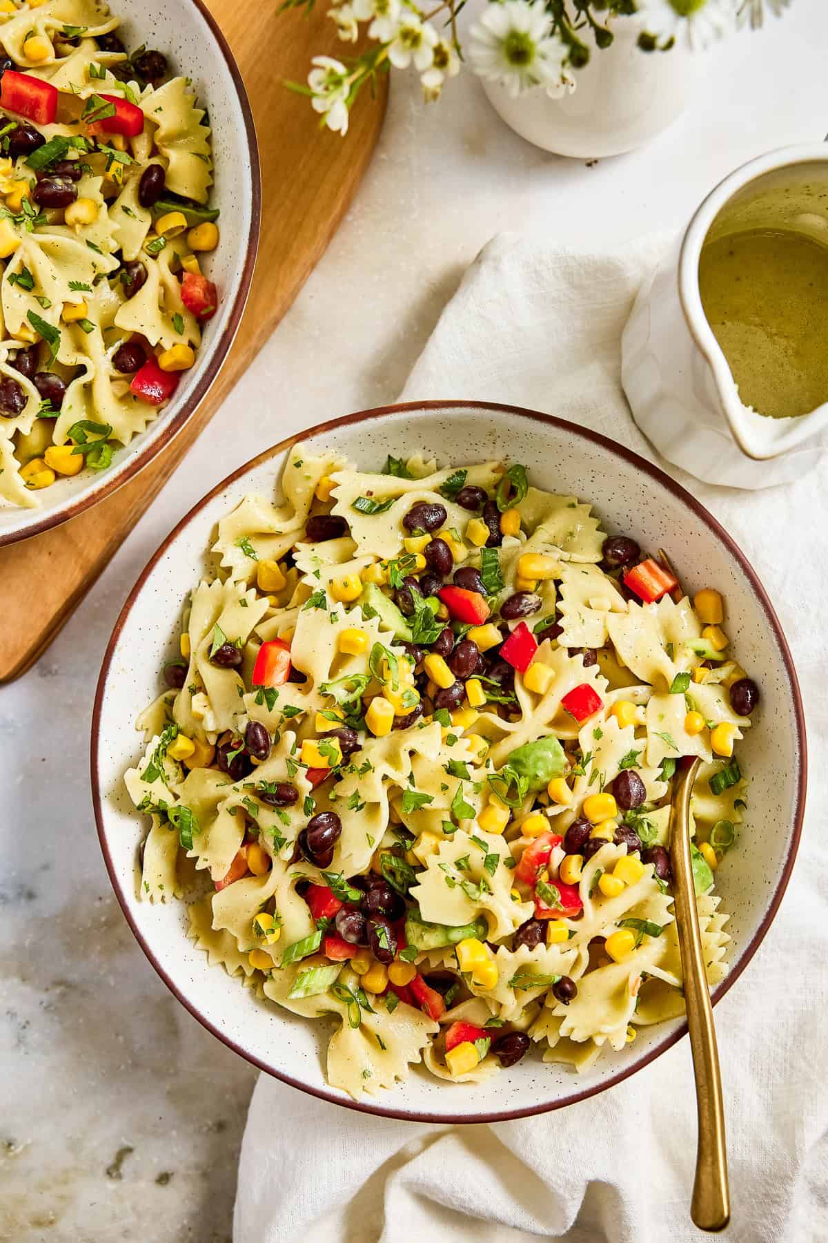 Southwest pasta salad in a bowl on a napkin with a spoon next to dressing.