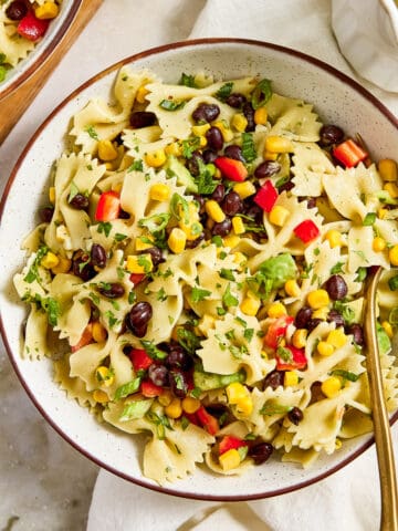 Southwest pasta salad in a bowl on a napkin with a spoon next to dressing.