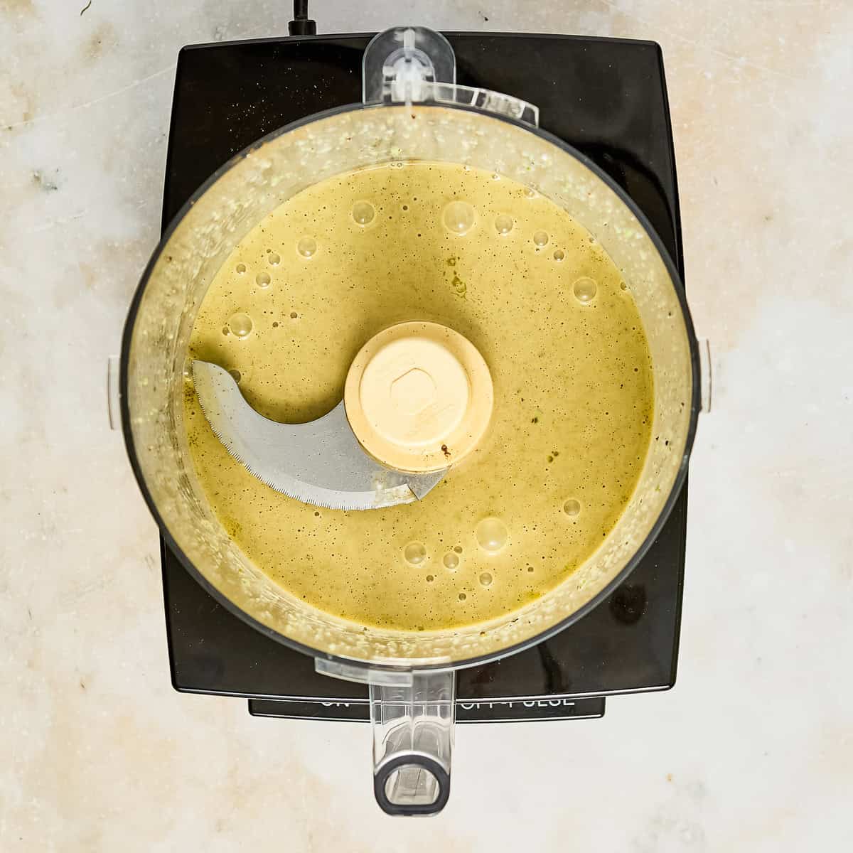 Blended honey lime jalapeño dressing in a food processor on a counter.