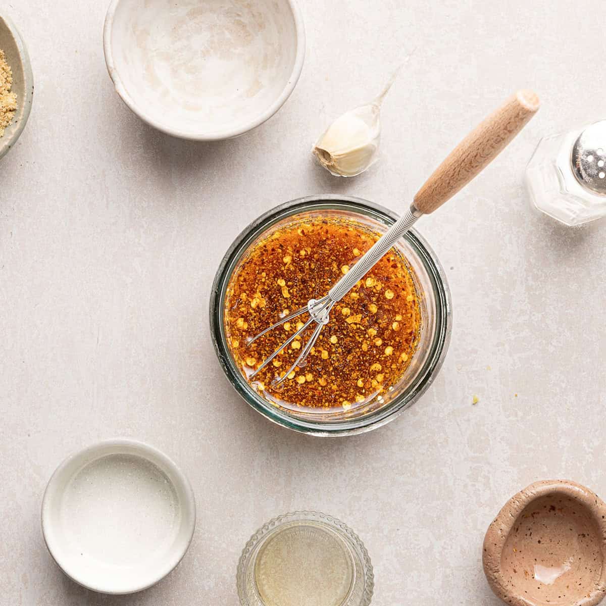 Sesame soy sauce dressing for cucumber salad in a small bowl with a whisk.