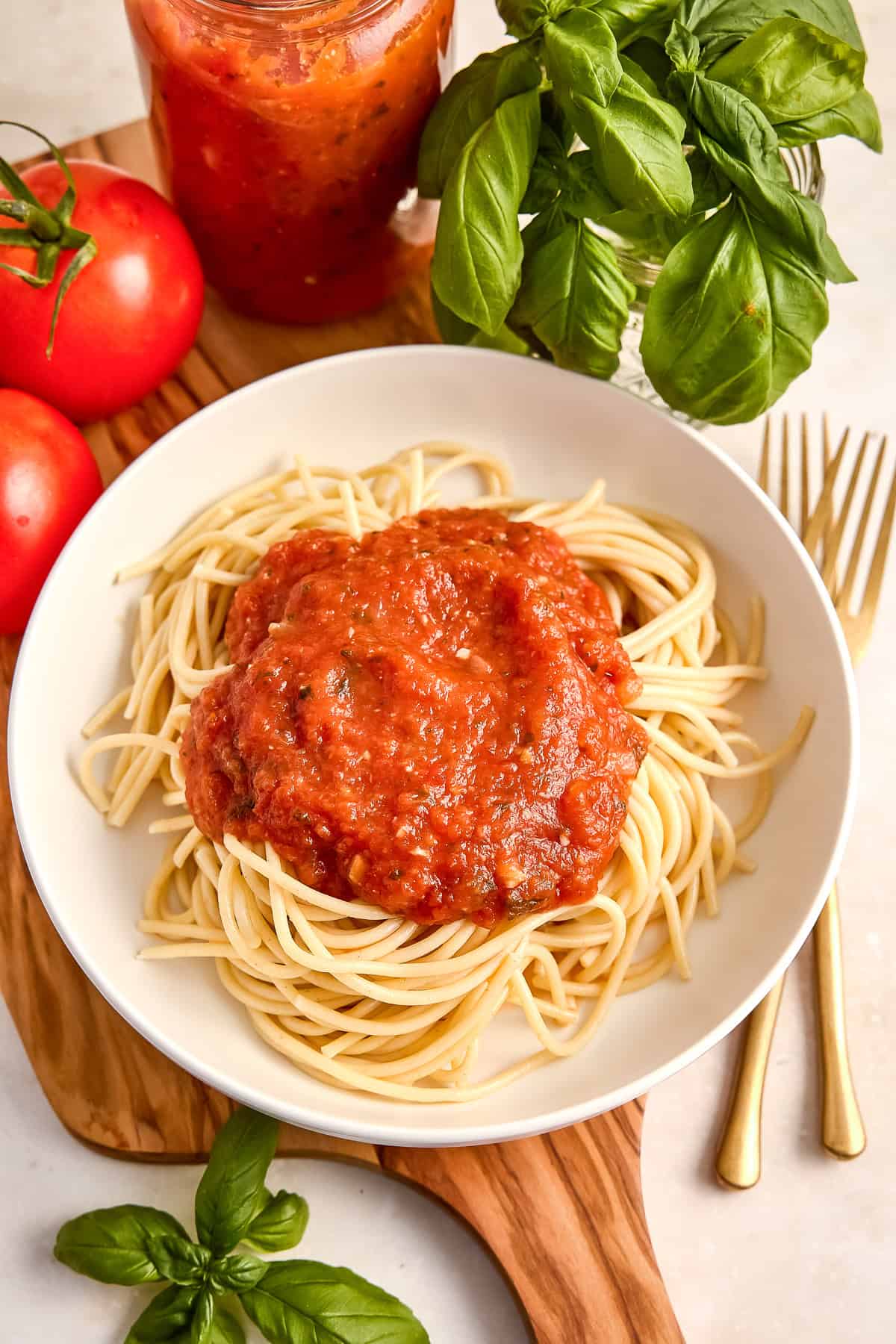 Homemade spaghetti sauce served over spaghetti in a bowl surrounded by ingredients.