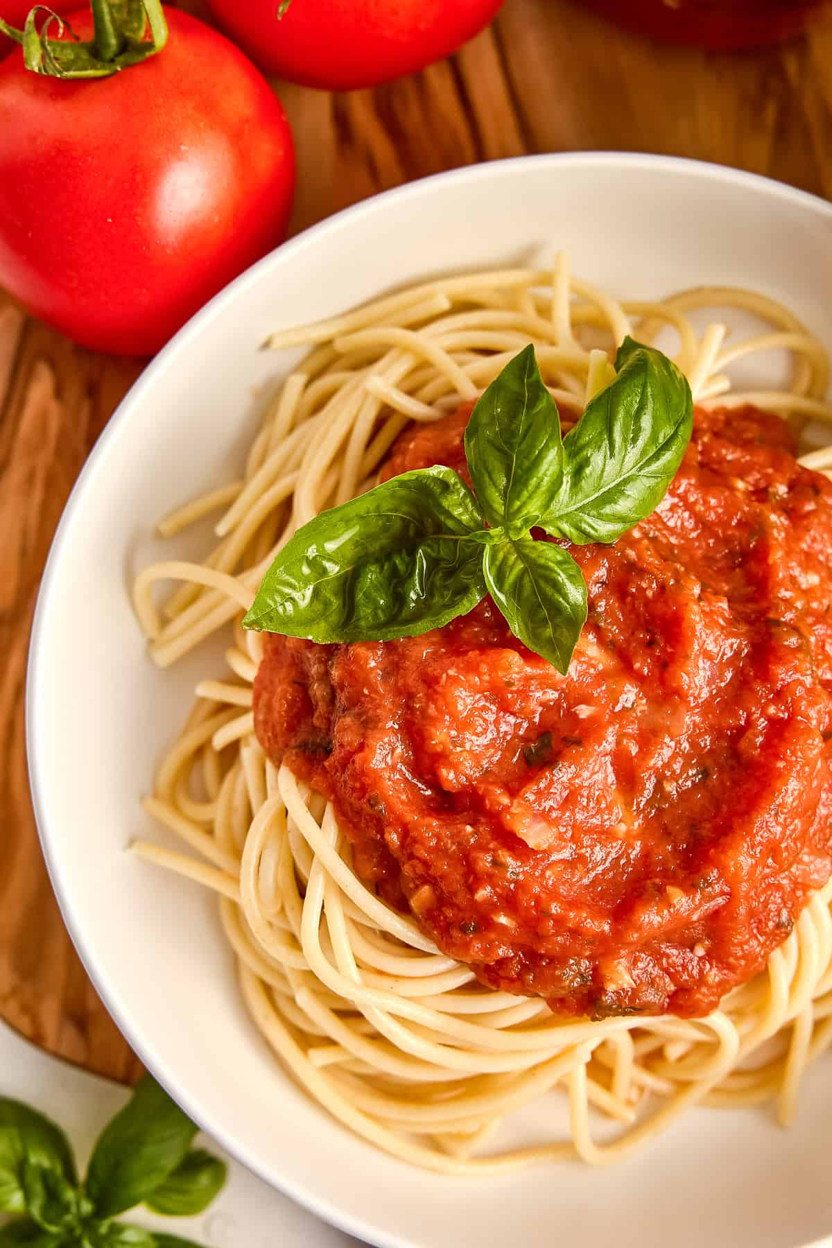 Fresh tomato sauce served over spaghetti and garnished with basil in a bowl.