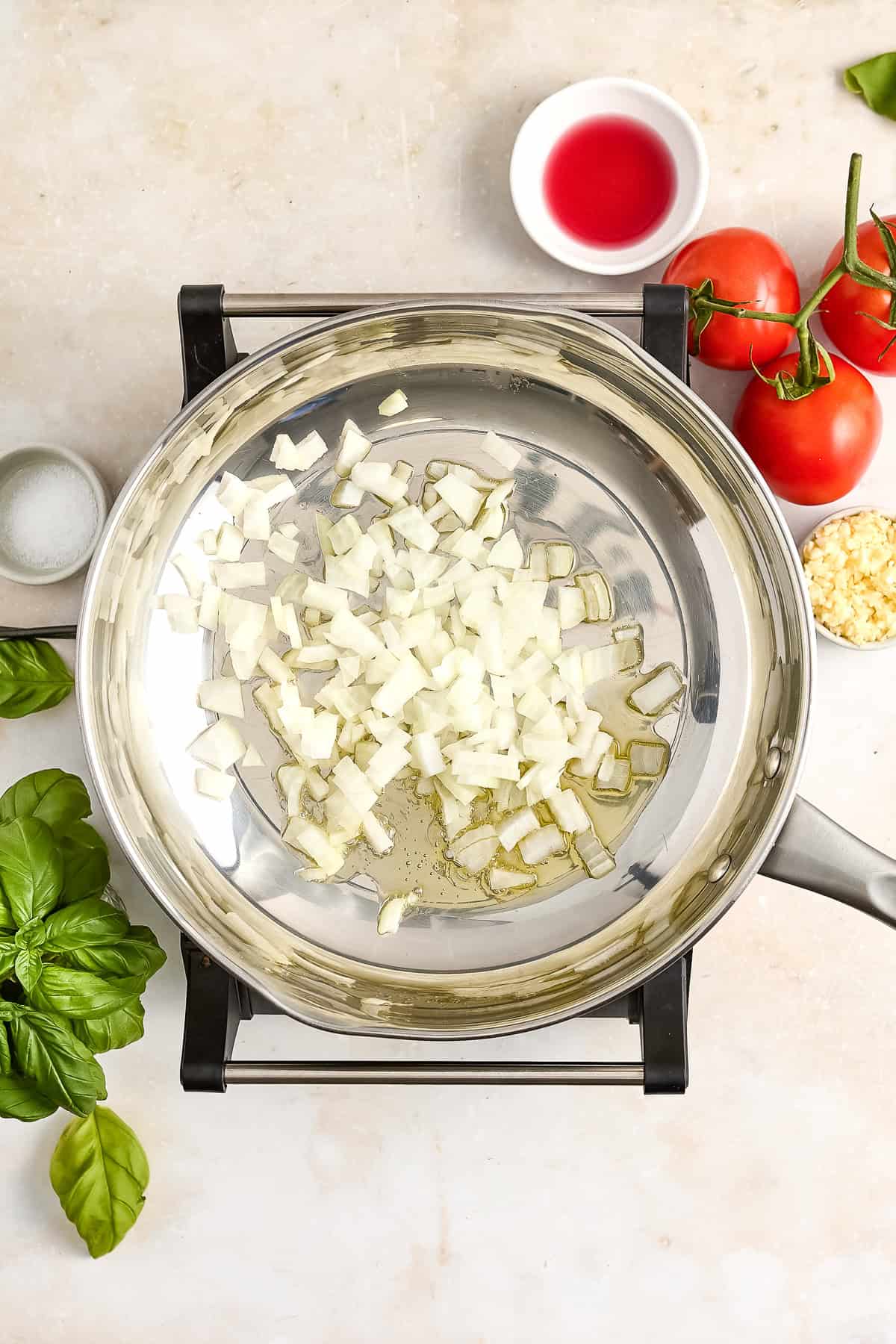 Diced onion cooking in olive oil in a saucepan over a stovetop.