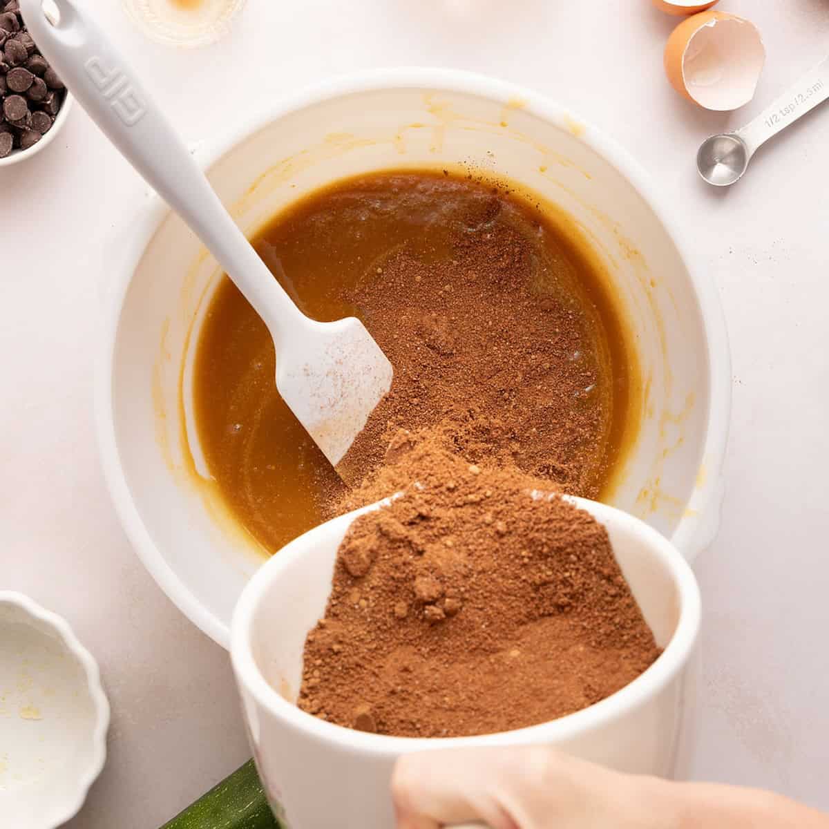 Woman transferring dry ingredients into the bowl with wet ingredients for brownies.