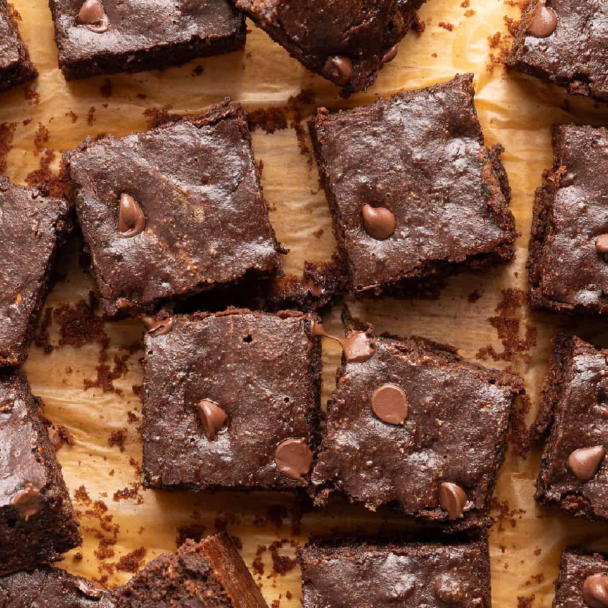 Zucchini brownies sliced into squares on a brown cutting board.