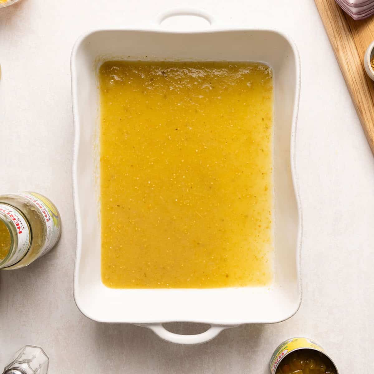Salsa verde spread on the bottom of a baking dish on a counter.