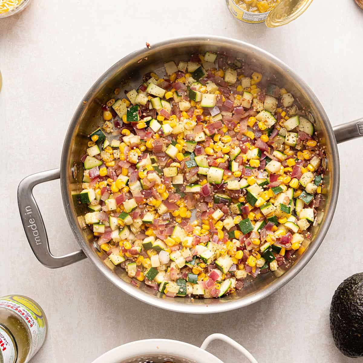 Zucchini, corn, onion, garlic, and seasonings cooked down in a skillet.