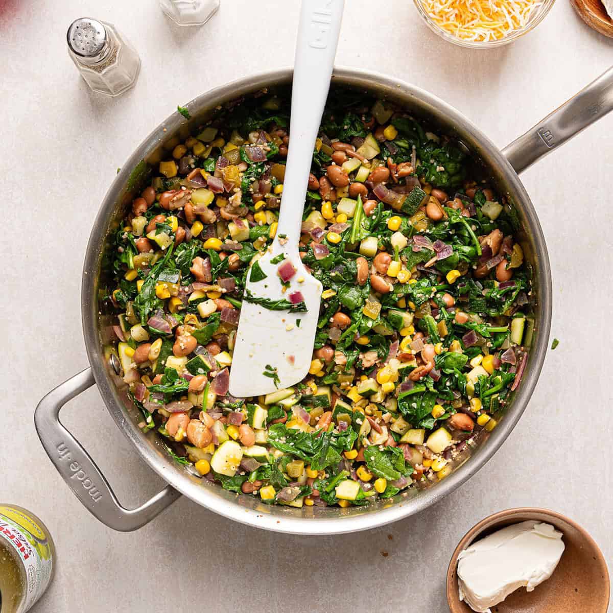 Vegetarian enchilada recipe filling cooked down in a large skillet with a spatula.
