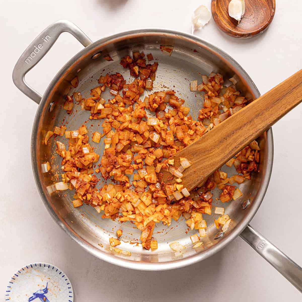 Onions cooked in red curry paste in a large skillet.