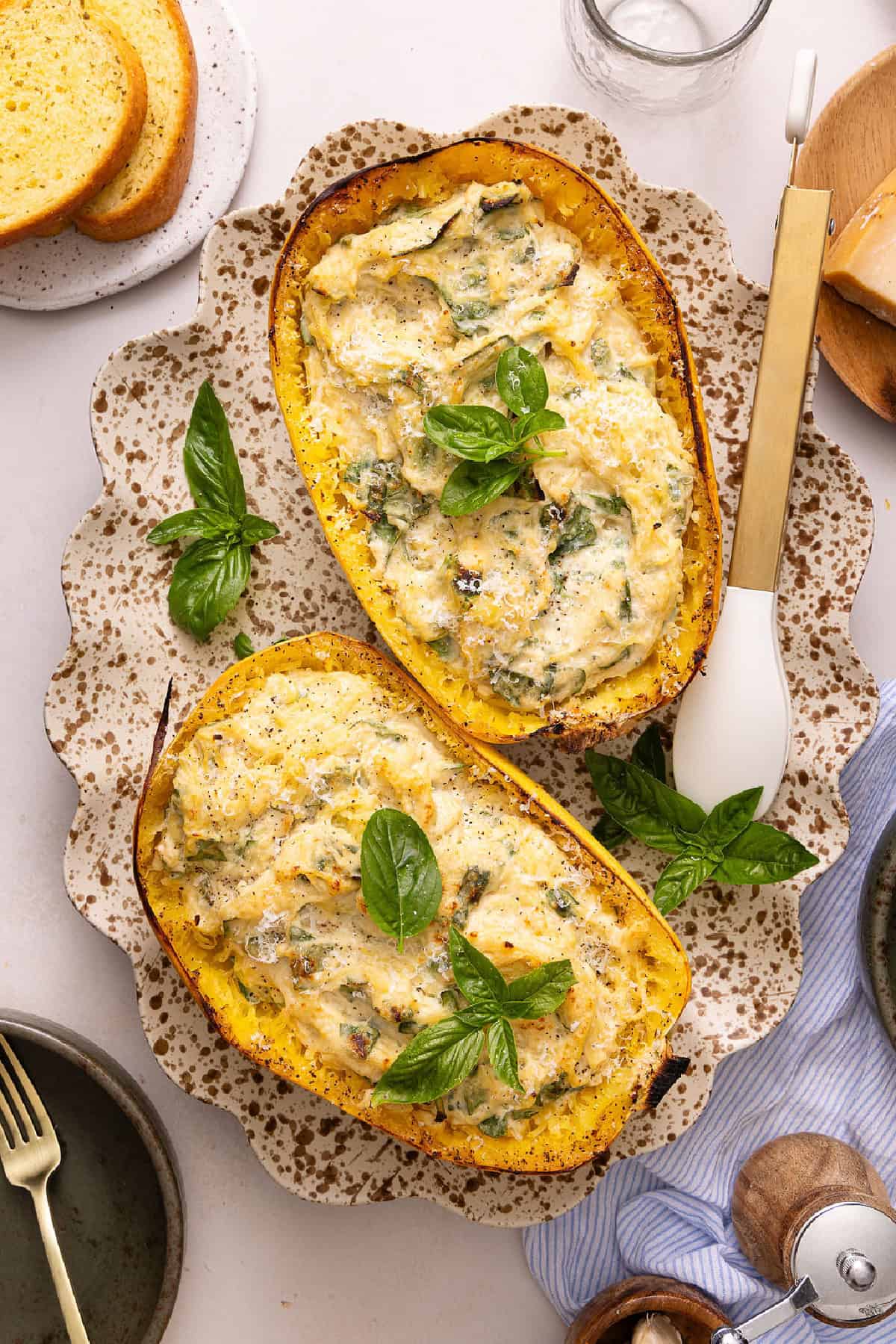 Two spaghetti squash alfredo boats topped with basil leaves on a serving platter.