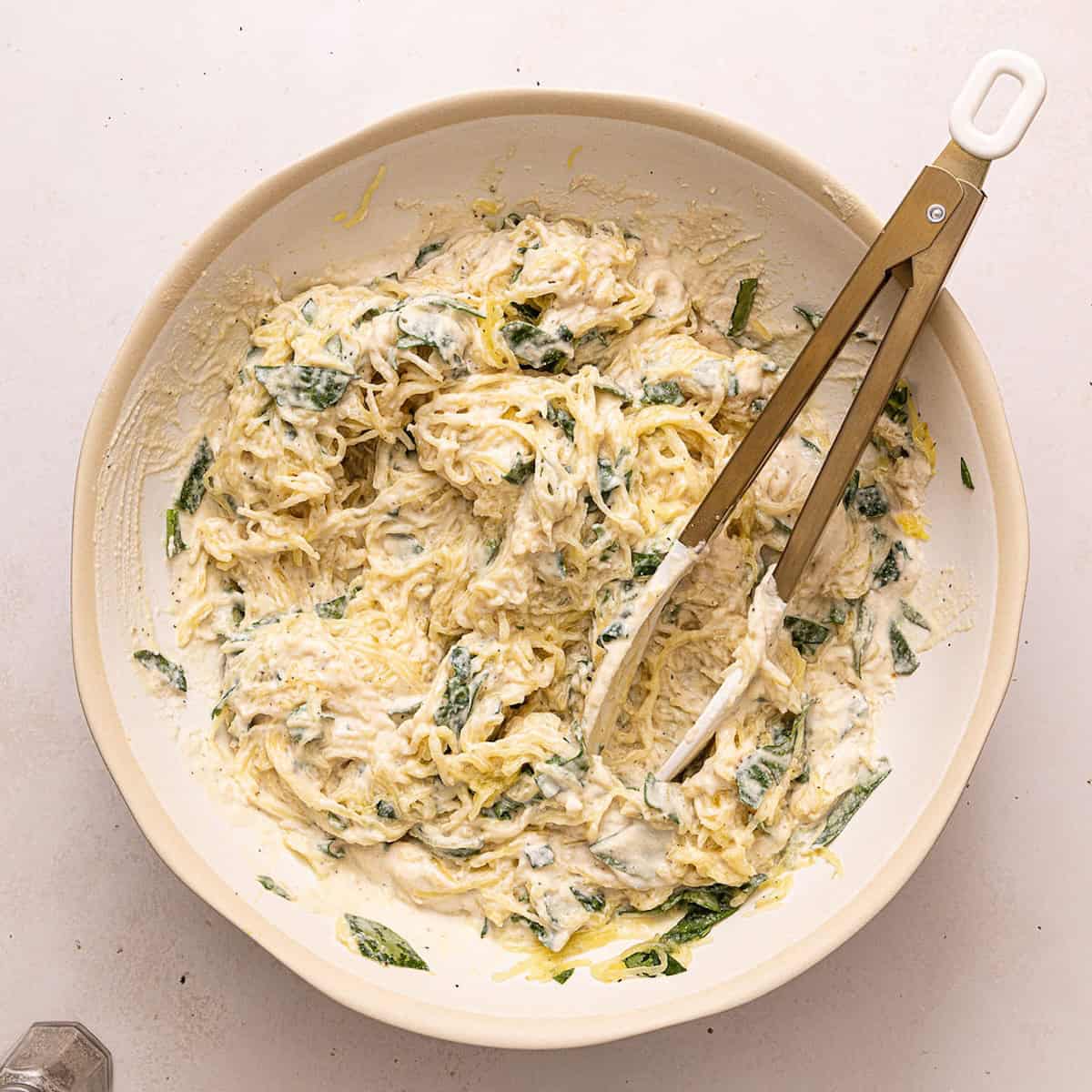 Spaghetti squash and spinach tossed with alfredo sauce in a bowl.