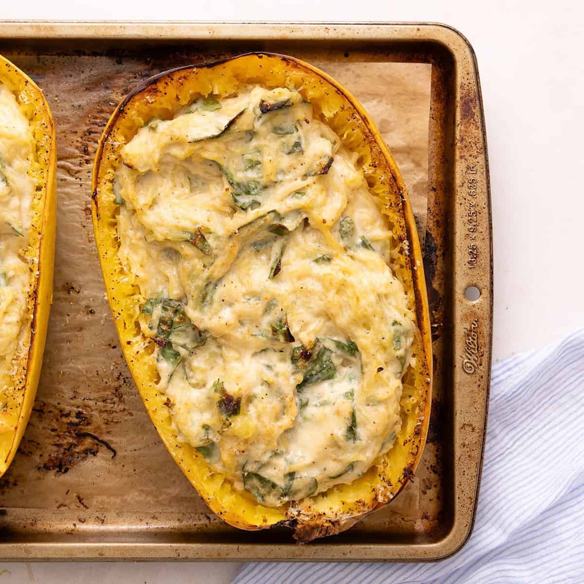 Spaghetti squash boat with alfredo, spinach, and melted cheese after coming out of the oven.